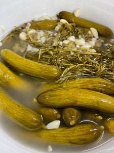 open bucket of freshly made lactofermented persian pickled cucumbers with tarragon and garlic